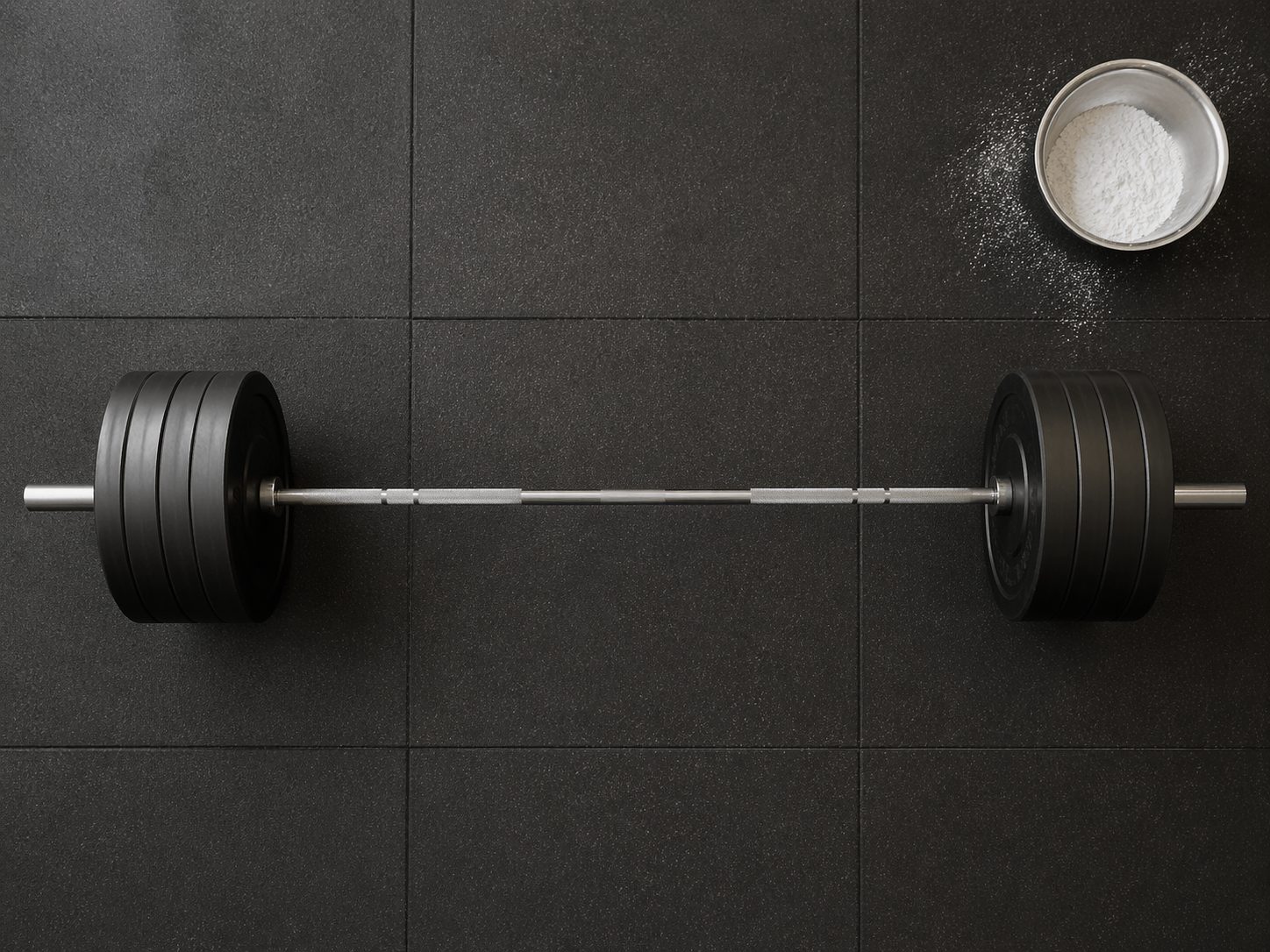 20kg Olympic barbell and stacked matte black bumper plates on horse-stall rubber mat, ProHeavyFitness